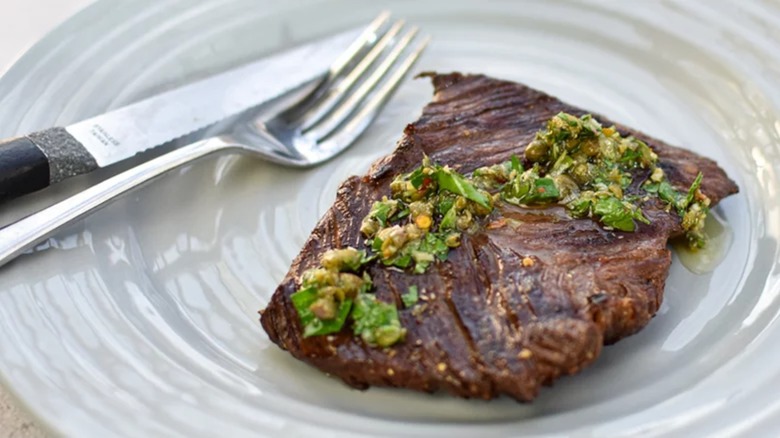 Grilled hangar steak on a plate with herby toppings