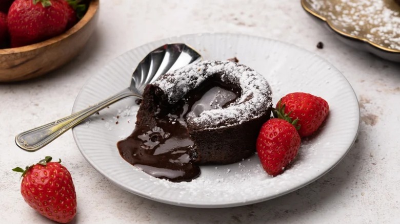 Miso chocolate lava cake with chocolate oozing out on a plate with strawberries