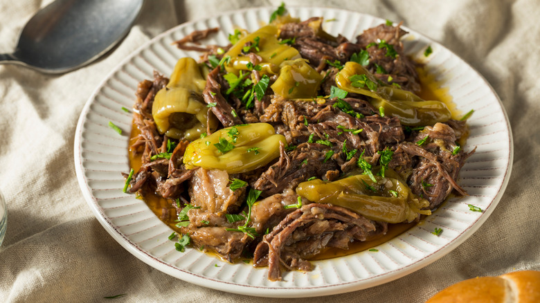 A plate of Mississippi pot roast on a linen tablecloth with a spoon to the side