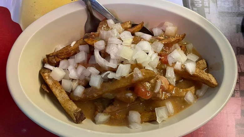 A bowl of the Slopper topped with onions and fries with forks in the bowl