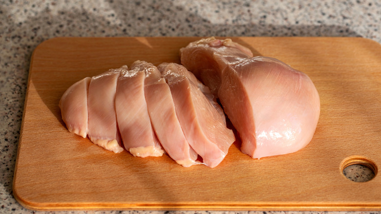 Chicken breast meat on wooden cutting board