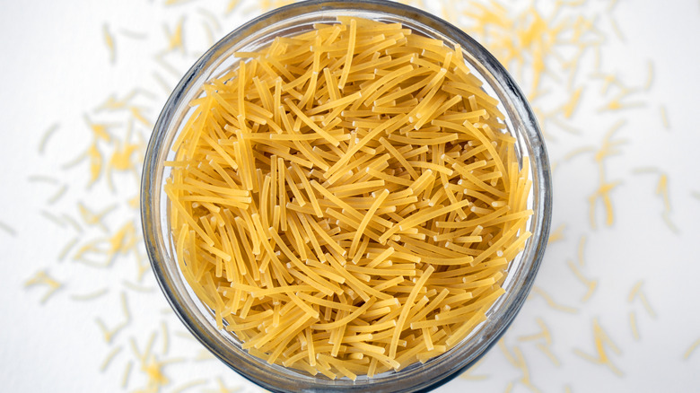 Glass jar raw pasta isolated on white background