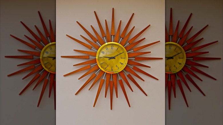A retro style wall clock with wooden sun shaped surround dating back to the 1970s
