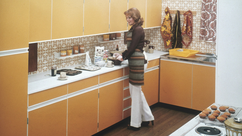 A woman baking cakes in a fitted kitchen, circa 1975