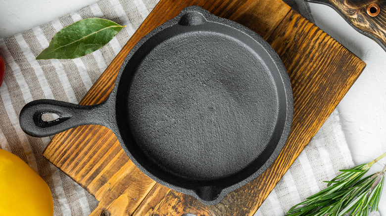 Cast iron skillet on cutting board with fresh herbs