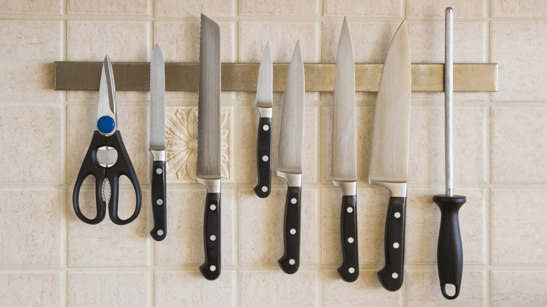 Several types of kitchen knives on kitchen tile wall