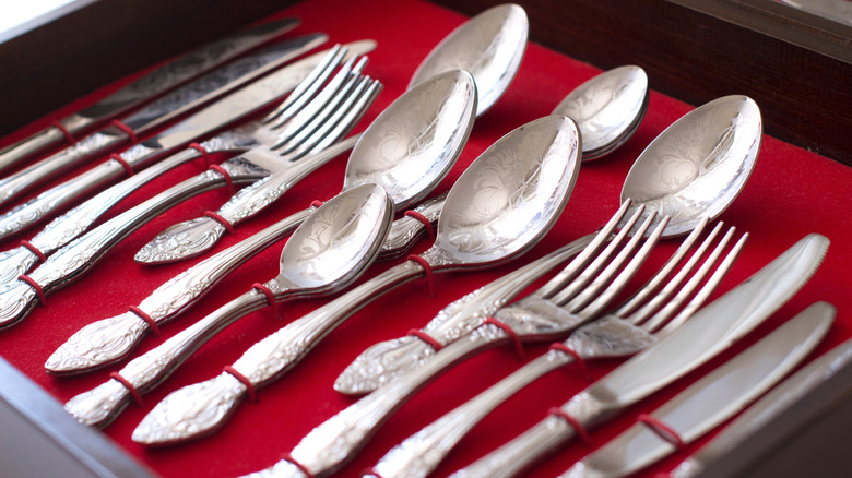 Silver cutlery in a wooden box with a red velvet lining