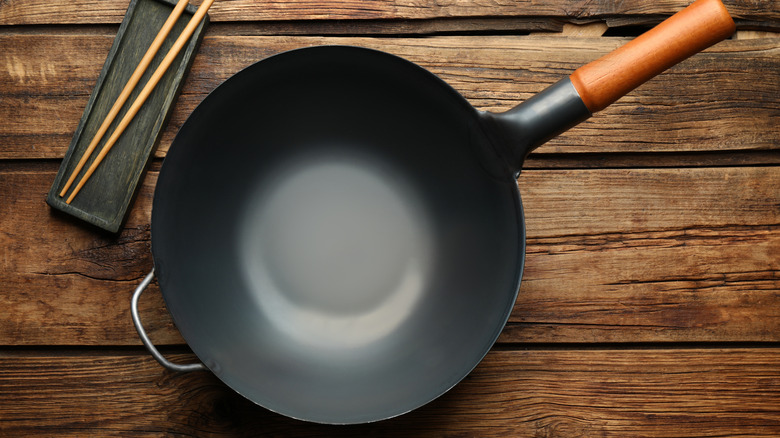 Wok with wooden handle on table with chopsticks