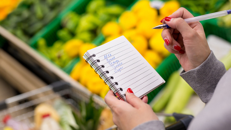 Woman with pen and grocery list in the produce department