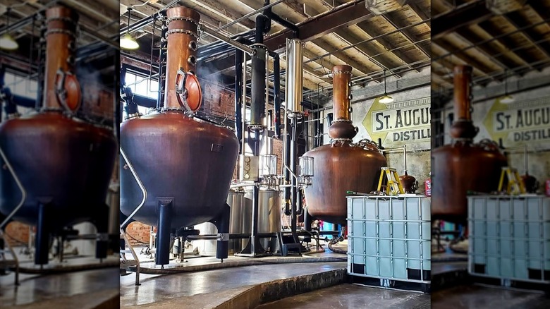 Large copper stills in a warehouse with the St. Augustine Distillery sign in the background