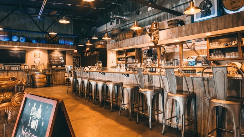 Interior picture of a bar with stools and a rustic, bourbon barrel inspired decor.