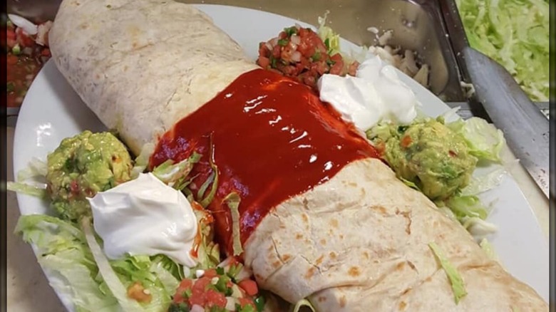 Monster Burrito on plate with lettuce, pico, sour cream, and guac
