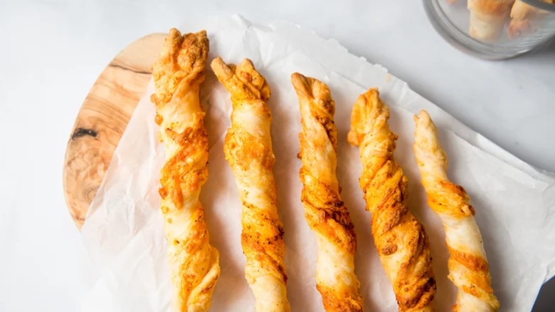 Air fryer cheese straws on parchment paper served on a wooden cutting board