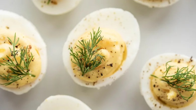 Deviled eggs topped with freshly-ground black pepper and fresh dill sprigs