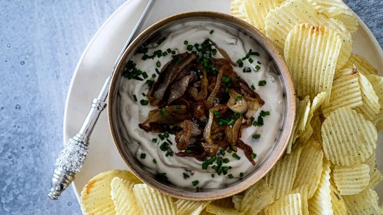 Luxe caramelized onion dip on a plate with a jeweled silver utensil and ridged potato chips
