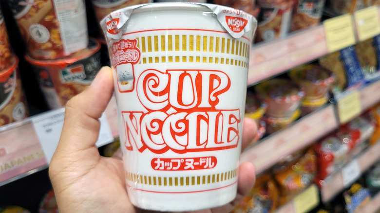 Hand holding a container of Cup Noodles with English and Japanese writing