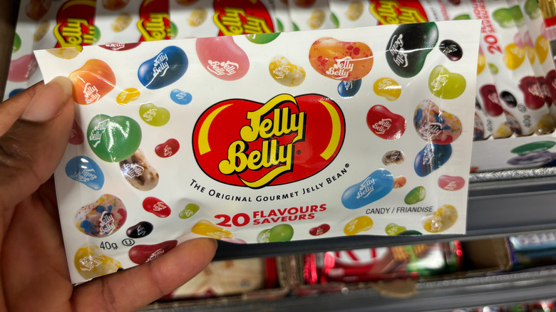 Hand holding a packet of Jelly Bellies with 20 flavors