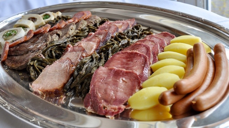 A Berner platte featuring smoked meats, sausages, potatoes, and dried green beans