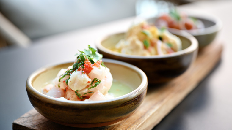 Bowls of ceviche on wooden board