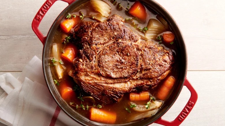 Pot roast with onions and carrots in a red Staub Dutch oven