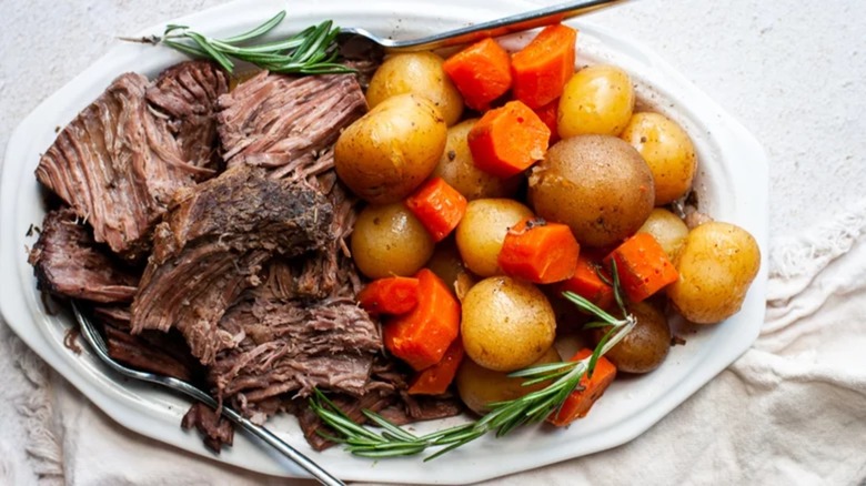 Rump roast with carrots, baby potatoes, and rosemary on a platter