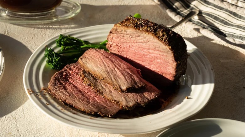 Sliced eye of round roast with broccolini on a plate