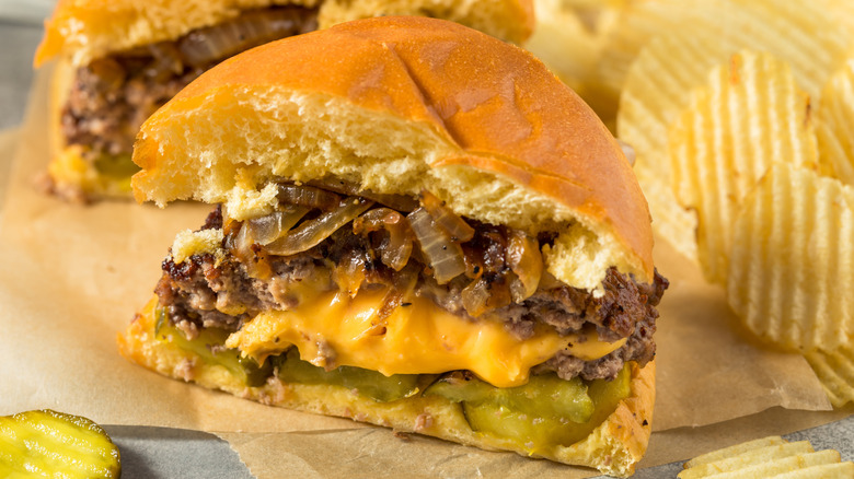 Juicy Lucy with onions and pickles cut in half with potato chips