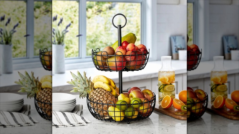 2-tiered wrought iron fruit stand on countertop with fruit and juice