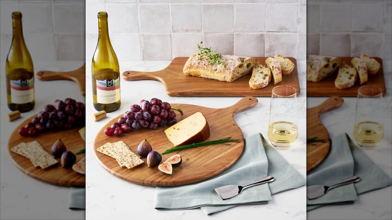Acacia charcuterie boards being used for cheese, fruit, and bread with wine