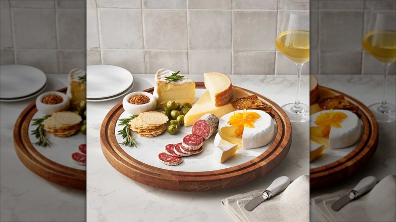 Acacia and marble lazy Susan with charcuterie on a marble countertop