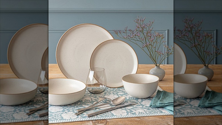 Dishware, cutlery, and napkins on top of a blue floral placemat