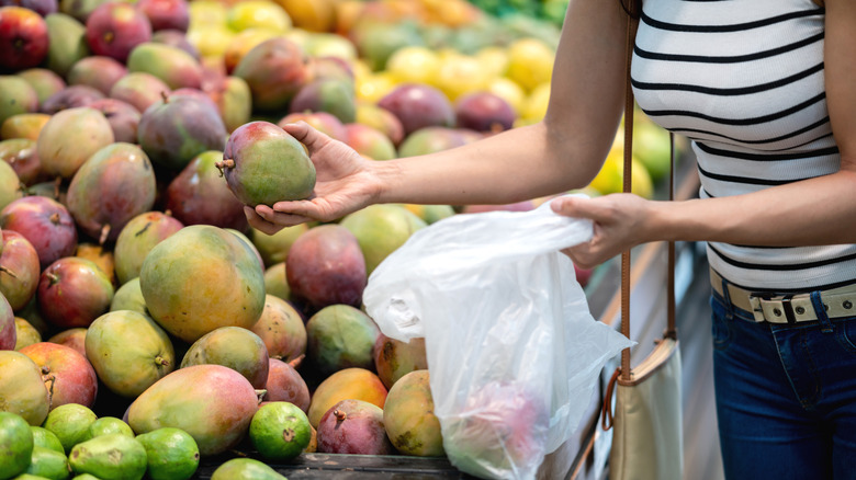 Woman picking out mangoes at grocery store