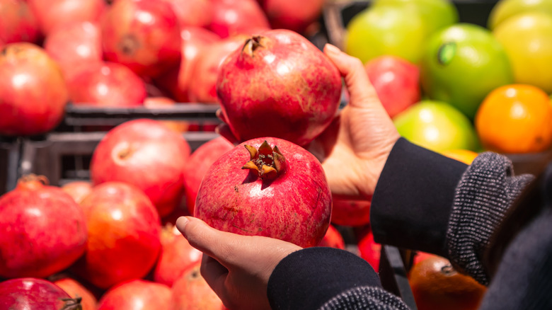 Person examining pomegranates at grocery store