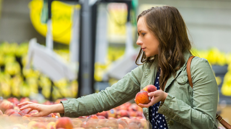 Woman choosing peaches at grocery store
