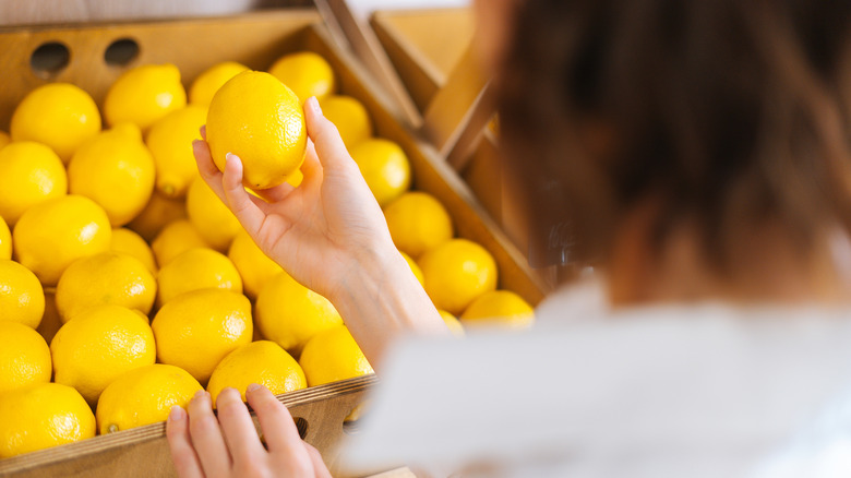 Person examining lemon at grocery store