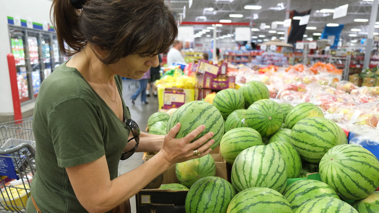 Woman examining watermelon at grocery store