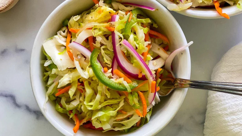 Bowl of colorful cabbage slaw with jalapeno and red onion