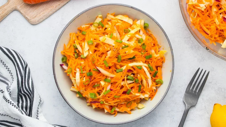 Bowl of carrot slaw garnished with chopped green onion