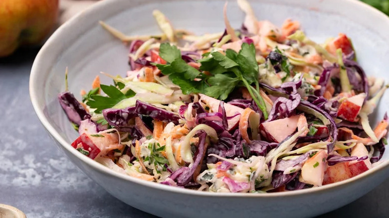 Bowl of cabbage and apple slaw with blue cheese and fresh parsley
