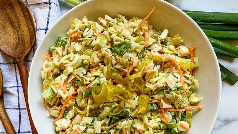 Coleslaw in white bowl, topped with pepperoncini