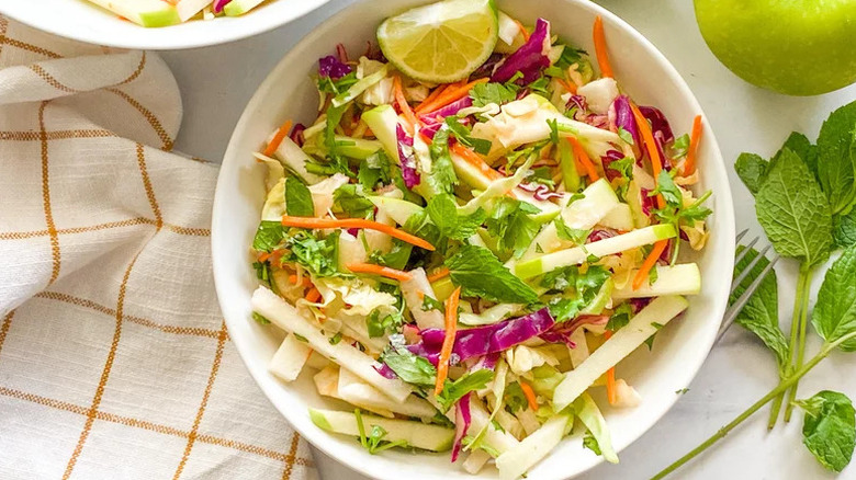 Bowl of colorful slaw garnished with cilantro and mint