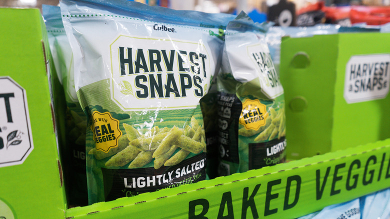 Bags of Harvest Snaps snacks in a green carton box in the store