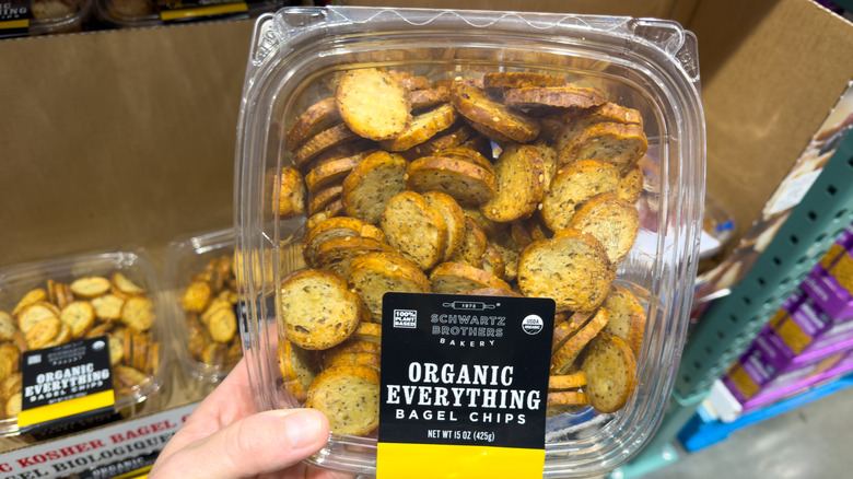 Hand holding a plastic container with small round crackers
