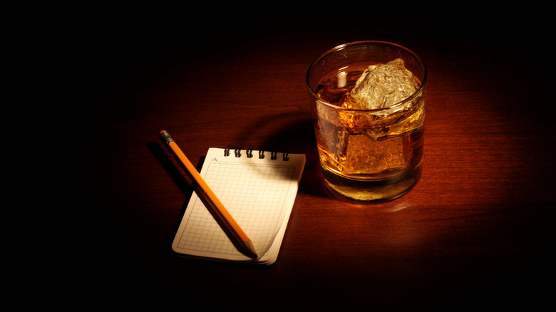 Glass of bourbon and a notepad