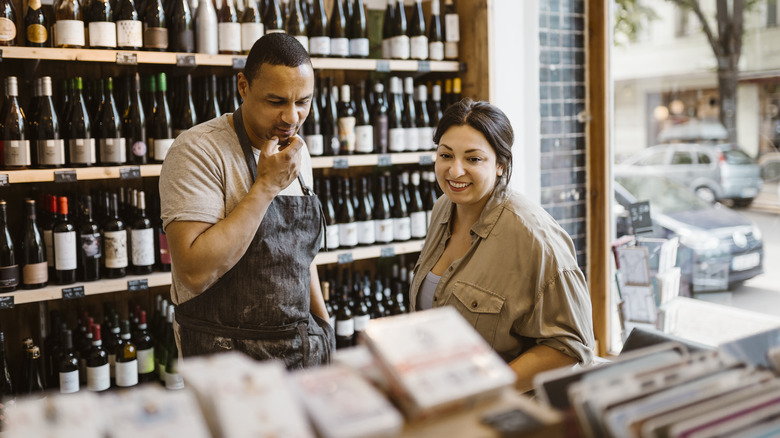 A worker and a buyer in a liquor store having a conversation