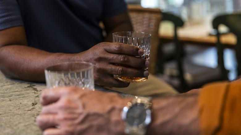 Two people sharing a drink together while holding glasses of whiskey