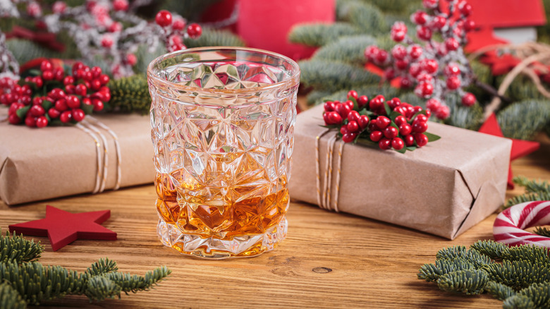 A glass of whiskey surrounded by gift boxes and decorations