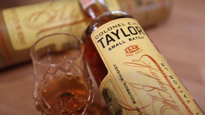 A close up of E.H. Taylor Small Batch laying down on its box, next to a filled glass