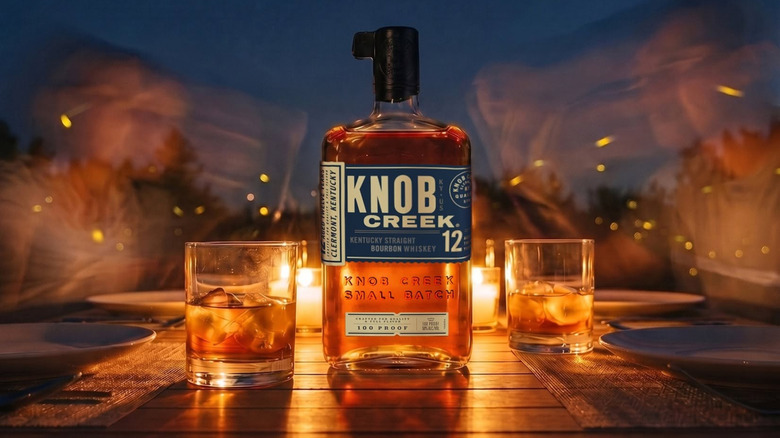 A stylized outdoor product shot of Knob Creek 12-year in front of candlelight and blurred people