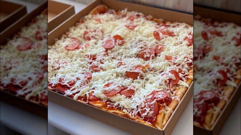 A square pizza with cold shredded cheese and pepperoni on top